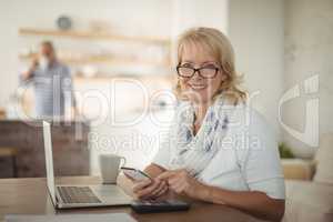 Senior woman using mobile phone at home