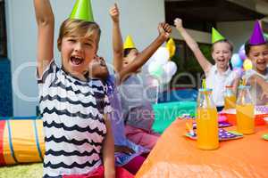 Children with arms raised shouting during party