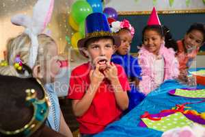 Boy making face while sitting with friends