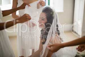 Bridesmaid assisting bride in wearing veil