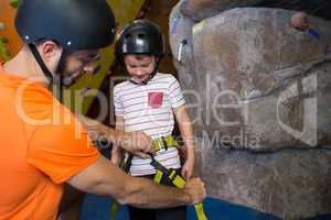 Trainer assisting boy to wear safety harness