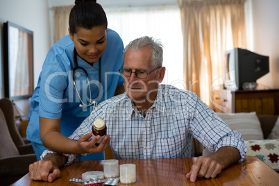 Female doctor assiting senior man in taking medicine