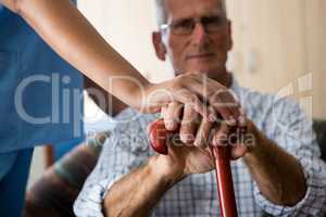 Close up of female doctor and senior man hands holding walking cane