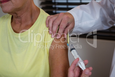 Physiotherapist injecting senior patient