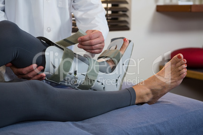 Physiotherapist tying leg pad