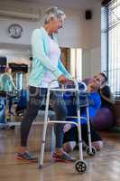 Physiotherapist assisting patient to walk with walking frame