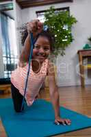 Smiling girl performing exercise on exercise mat