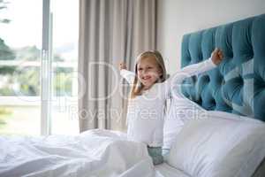 Girl stretching her arms while waking up in bedroom
