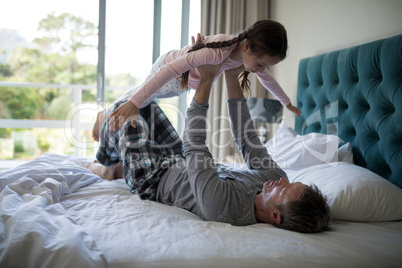 Happy father and daughter having fun on bed in bedroom