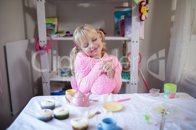 Cute girl daydreaming while playing with toy kitchen set