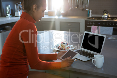 Young woman using tablet in kitchen