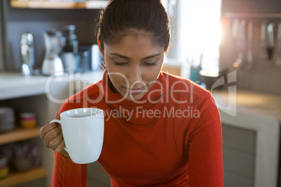 Woman holding coffee cup in kitchen