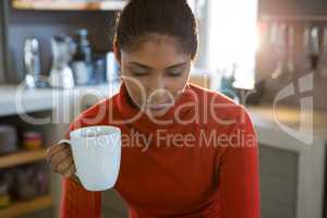 Woman holding coffee cup in kitchen