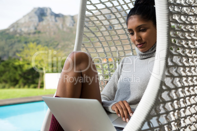Woman using laptop on swing chair