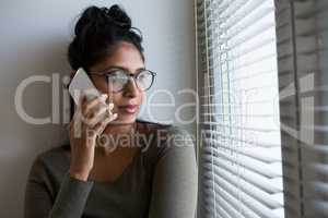 Woman talking on phone by window