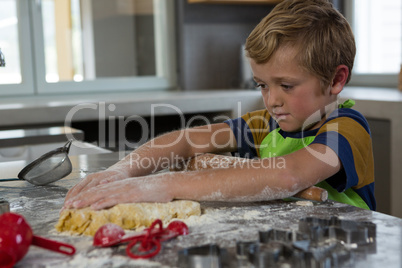 Boy baking dough in kitchen