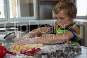 Boy baking dough in kitchen
