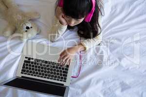 Girl with toy using laptop on bed