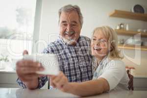 Senior couple taking a selfie in the kitchen