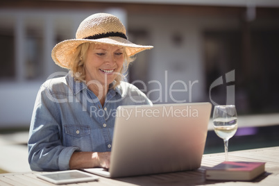 Senior woman using her laptop outside house