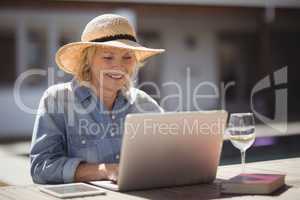 Senior woman using her laptop outside house
