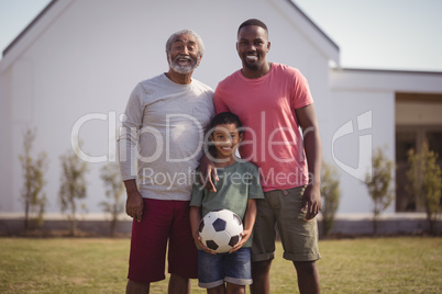 Happy multi-generation family standing in garden with football