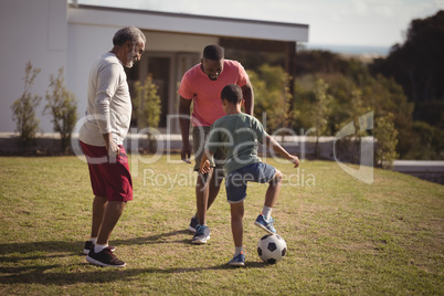 Boy playing football with his father and grandson