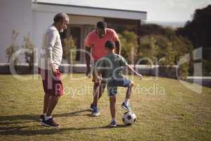 Boy playing football with his father and grandson