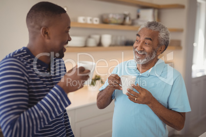 Smiling father and son interacting while having cup of coffee