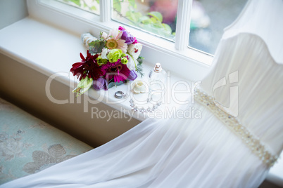 Bouquet of flower and wedding dress kept on window sill