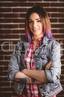 Smiling woman standing with arms crossed against brick wall