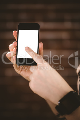 Woman showing mobile phone against brick wall