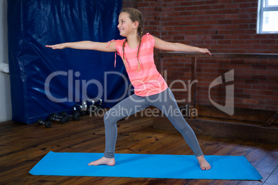Happy teenage girl performing warrior pose