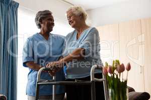 Nurse assisting senior patient in walking with walker
