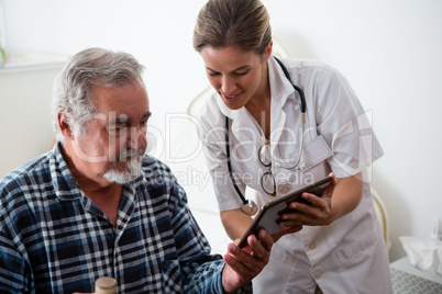 Female doctor showing digital tablet to senior man