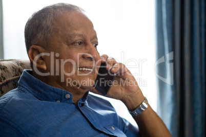Smiling senior man talking on mobile phone in nursing home