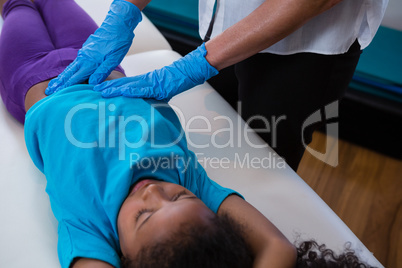 Physiotherapist giving abdomen massage to girl patient