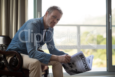 Man sitting on chair and reading newspaper in living room