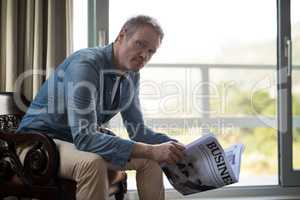 Man sitting on chair and reading newspaper in living room