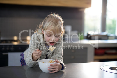 Little girl eating cereals rings with spoon from a bowl