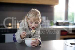 Little girl eating cereals rings with spoon from a bowl