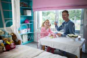 Girl and father having tea from the toy kitchen set
