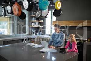 Father using a laptop while daughter is using a tablet