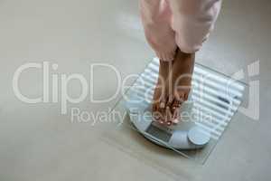 Low section of woman standing on bathroom scale