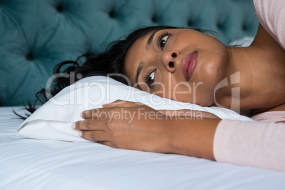 Thoughtful woman lying on bed