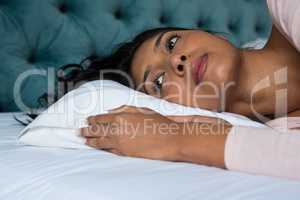 Thoughtful woman lying on bed