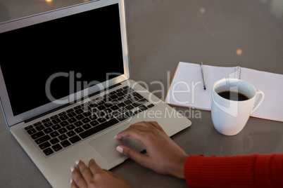 Cropped hands of woman using laptop at kitchen counter