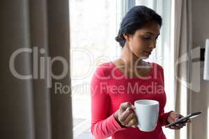 Young woman with coffee cup using phone