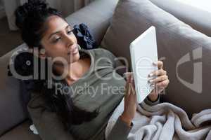 Woman using digital tablet on sofa