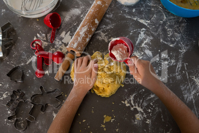 Cropped hand of boy putting flour on dough
